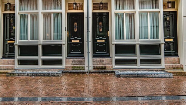 A row of brick townhouses with large windows and black doors. - Luxury Apartment with spacious living room (Amsterdam)