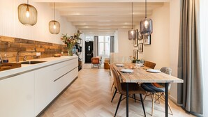 A modern kitchen with a wooden backsplash, a central island, and pendant lighting. - Luxury Apartment with spacious living room (Amsterdam)