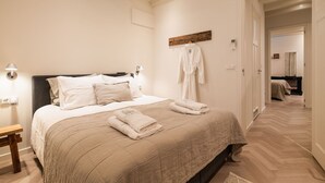 A bedroom with a bed, bedside table, and a robe hanging on the wall.