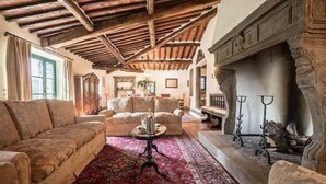 Un soggiorno tradizionale con soffitto in legno, camino e arredamento classico.