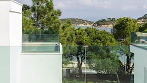 A modern building with a glass balcony overlooking a coastal landscape with trees and hills. - Villas Acrotel Porto Brava, Ormos Panagias-formerly TUI Ferienhaus (Sithonia)