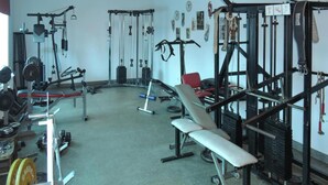 Un gimnasio con diversos equipos de ejercicio, incluyendo máquinas de pesas, bancos y pesas libres.