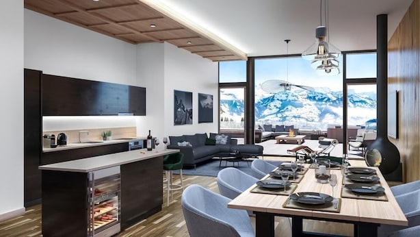 A modern kitchen with a built-in refrigerator, a dining area with a wooden table and chairs, and a large window offering a view of snow-capped mountains. - Wifi, 100m from ski slopes, sauna, hammam, terrace, parking, ski locker, 103m², Peisey-Vallandry (Mâcot-la-Plagne)