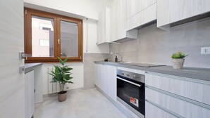 A modern kitchen with white cabinetry, a built-in oven, and a window with wooden frames.
