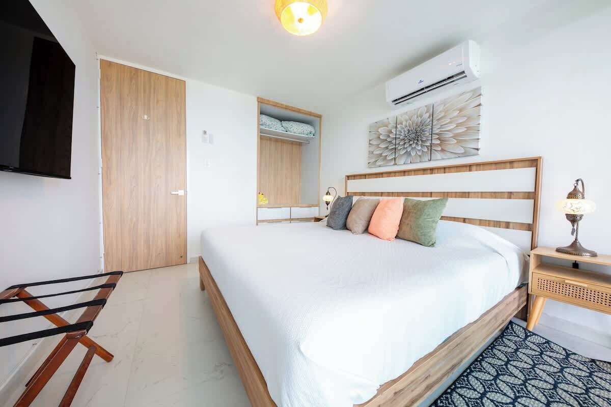 Un dormitorio con cama, armario de madera, estante empotrado, aire acondicionado de pared y lámpara de noche.
