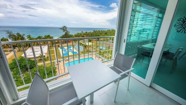 A balcony with a view of the ocean and a swimming pool.