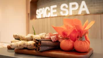 A wooden tray with ginger, cinnamon sticks, and small pumpkins on a counter.