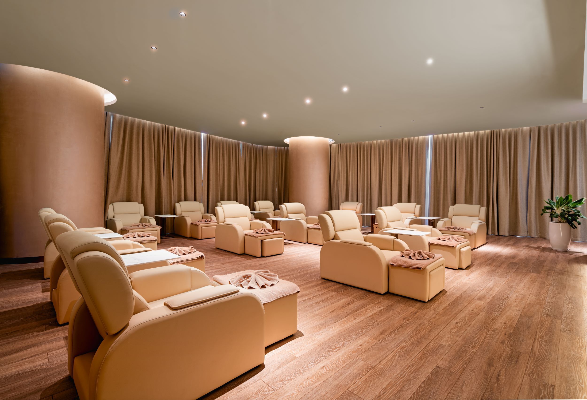 A spa room with multiple massage chairs, a large pillar, and a potted plant.