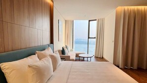 Ein modernes Hotelzimmer mit einem großen Bett, einer Sitzecke und Meerblick.