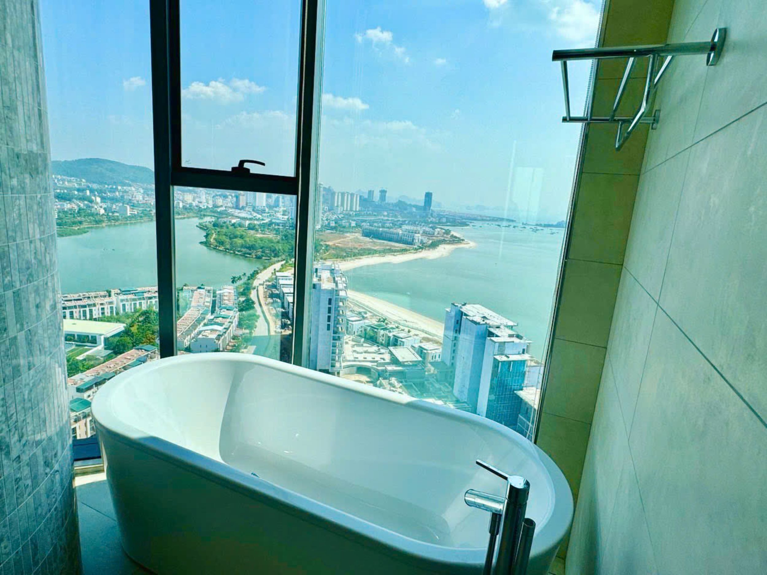 A bathroom with a freestanding bathtub, large windows offering a city view, and a modern design.
