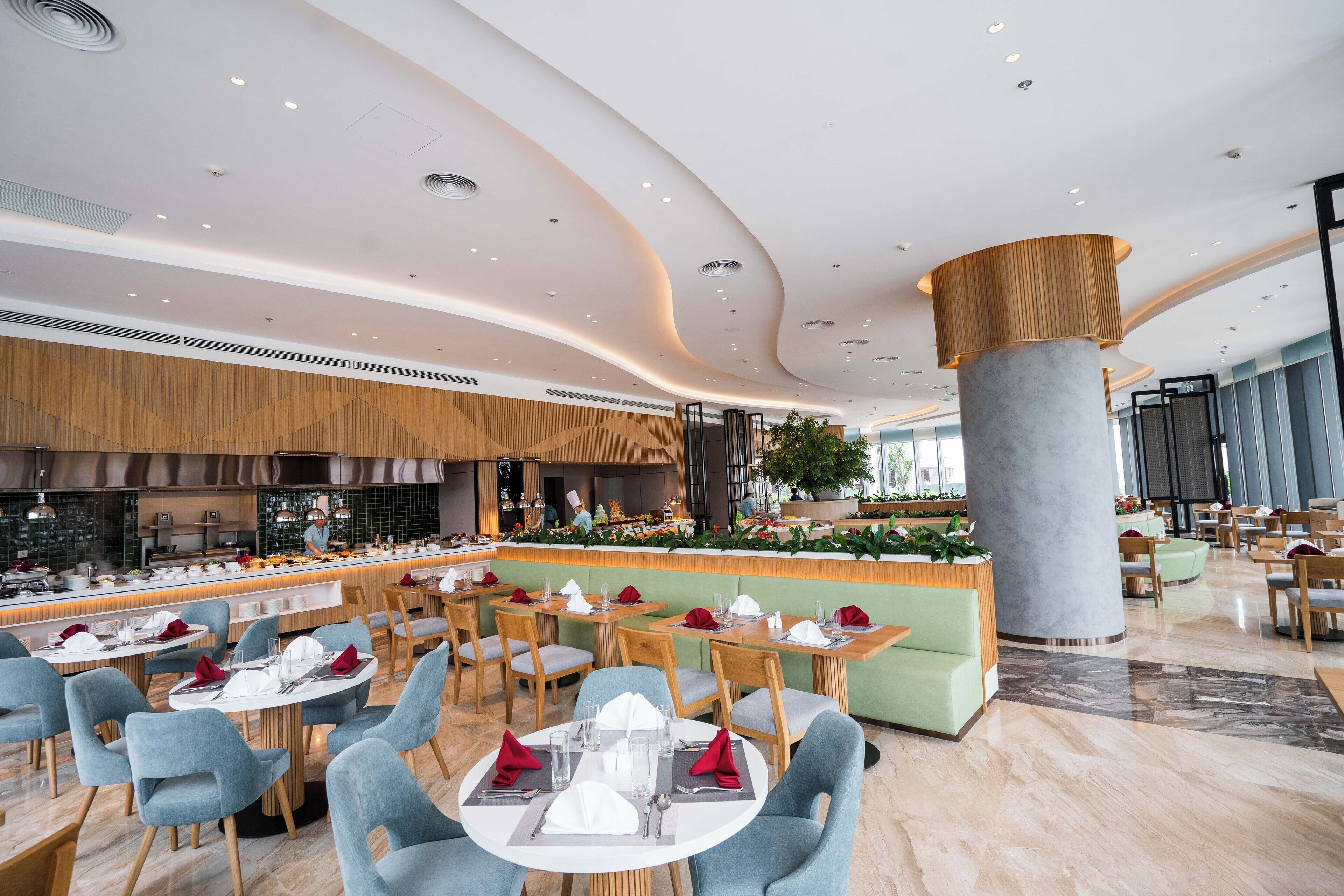 A modern restaurant with round tables, blue chairs, and a central bar area.