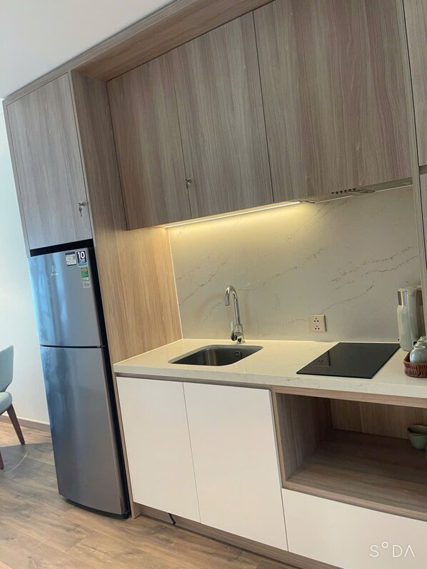 Una cocina moderna con armarios de madera, un refrigerador de acero inoxidable, un lavamanos doble y una encimera de mármol.