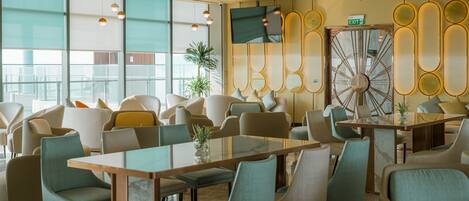 A modern conference room with glass tables, comfortable chairs, and a large wall clock.
