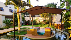 A pool area with a sunken seating area, surrounded by a garden with various plants and a pathway. - Azcapri Villa-Boutique & Spa (Cancun)
