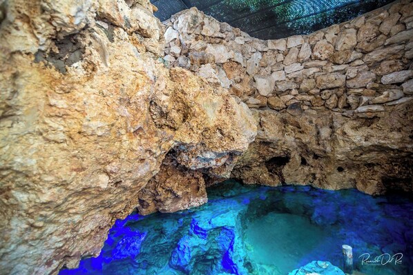 A cave interior with natural rock formations and clear blue water. - Azcapri Villa-Boutique & Spa (Cancun)