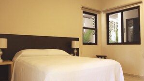 A hotel room with a bed, two bedside lamps, a nightstand, and a window with a view of greenery. - Azcapri Villa-Boutique & Spa (Cancun)