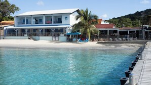 Ein Strandhotel mit Pool, einer Palme und einem Steg.