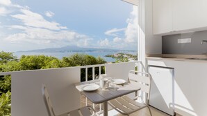 Ein Balkon mit Tisch für zwei Personen, mit Blick auf eine malerische Wasserlandschaft und das entfernte Ufer.