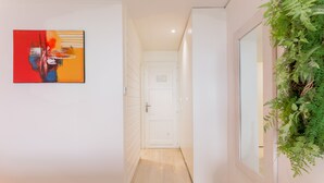 Ein Flur mit einer weißen Tür, einem Bild an der Wand und einer grünen Pflanze.
