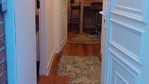 Un pasillo estrecho con piso de madera que conduce a un comedor con una mesa y sillas.