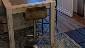 Un comedor con una mesa y sillas de madera, un tapete estampado y vistas al exterior por una puerta.
