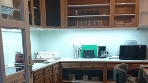 Una cocina pequeña con armarios de madera, un microondas y una tetera.