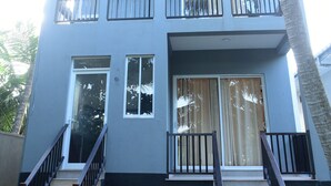 Un edificio de varios pisos con techo plano, balcones y una escalera que lleva a la entrada.