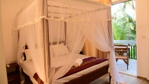 Una cama con dosel, un banco de madera y vistas a la vegetación exterior.