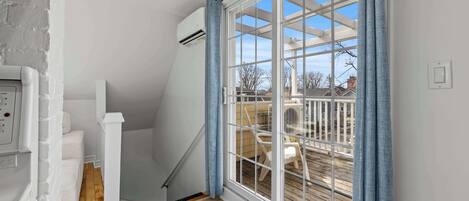 Um quarto com piso de madeira, parede branca, janela com cortinas azuis e teto branco.