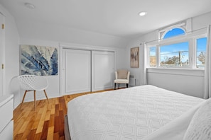 A bedroom with a large bed, a chair, a wardrobe, and a painting on the wall.