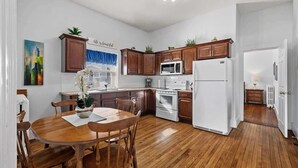Una cocina moderna con armarios de madera, un refrigerador blanco y una zona de comedor con una mesa y sillas de madera.