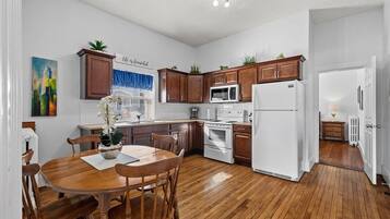 A kitchen with wooden cabinets, a white refrigerator, and a dining table with chairs.