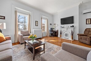 A living room with a fireplace, a television mounted on the wall, and a comfortable seating area with sofas and a coffee table. - Spacious Downtown Retreat at Ole King Square (Charlottetown)