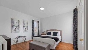 A bedroom with a bed, a bench, and artwork on the wall. - Downtown Urban Comfort Spacious 1 Bdrm Apartment (Charlottetown)