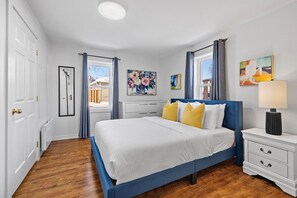 Une chambre à coucher avec un lit, une table de chevet et des œuvres d’art accrochées aux murs.
