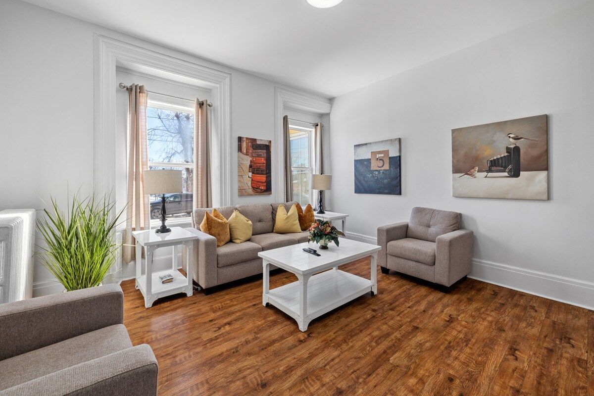 A modern living room with a sofa, armchairs, a coffee table, and artwork on the walls.