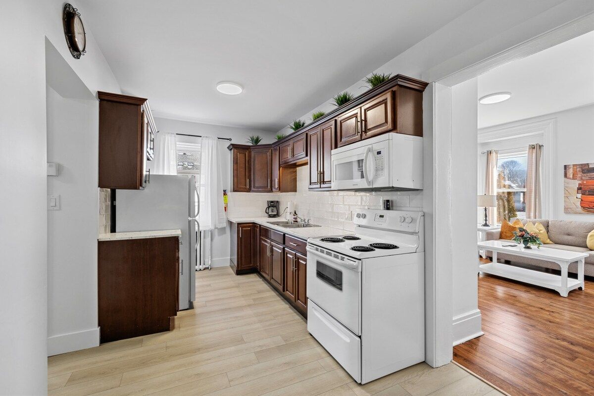 A modern kitchen with white appliances, wooden cabinets, and a central island.