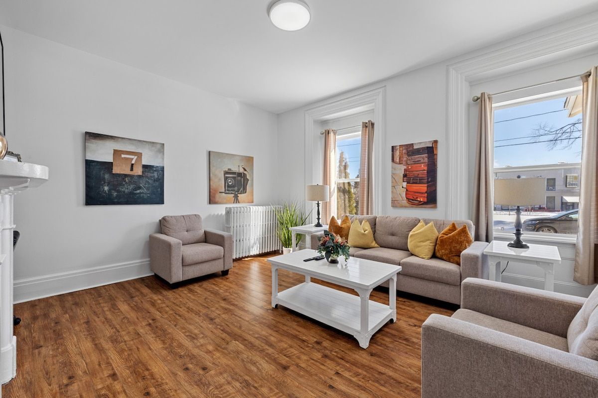 A modern living room with a wooden floor, a sofa set, a coffee table, and artwork on the walls.
