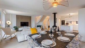 Ein modernes Wohnzimmer mit Essbereich, einer Treppe und einer Küche.