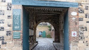 Ein rundbogiges Steintor, das zu einem Kopfsteinpflasterweg führt.