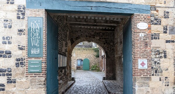 Un arco de piedra que da paso a un sendero adoquinado.