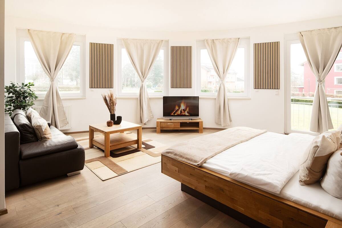 Une chambre moderne avec un lit, un canapé, une télévision et une petite table.