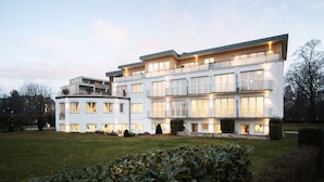 Een modern meerlaags appartementencomplex met een plat dak, grote ramen en een verzorgd gazon.