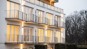 Een meerhoog gebouw met balkons en grote ramen, omringd door bomen.