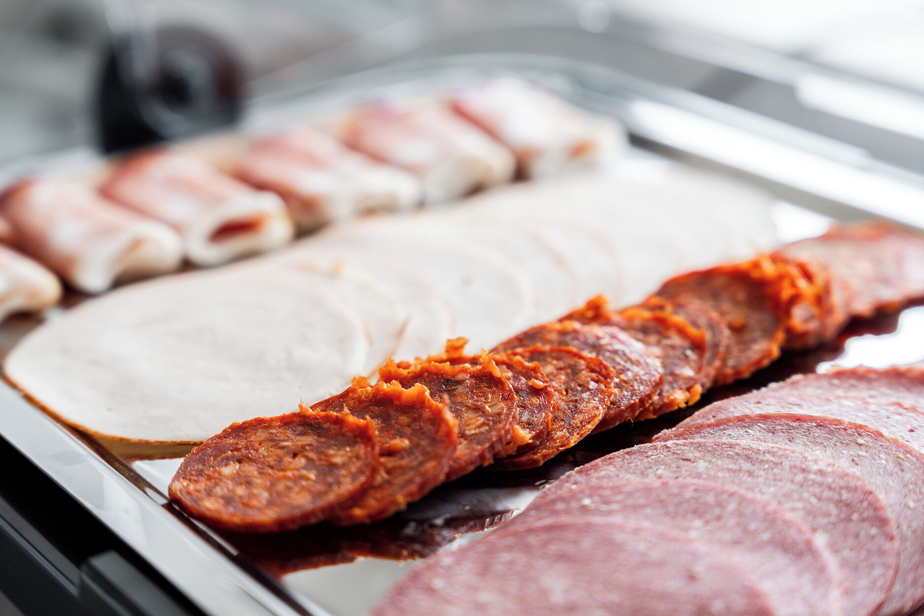 A display of various meats including sliced sausages and hams.