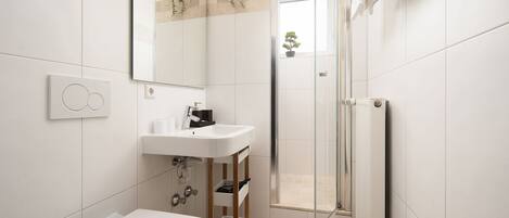 Un baño moderno con lavamanos, inodoro y ducha blancos.