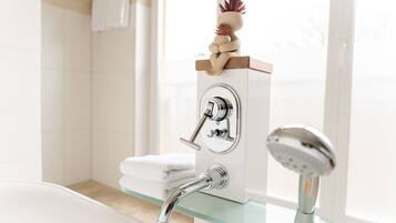 A modern bathroom with a glass-enclosed shower, a wall-mounted faucet, and a decorative plant on a shelf.