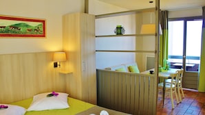 Ein Hotelzimmer mit zwei Betten, einem kleinen Tisch, einem Stuhl, einem Fenster mit Vorhängen und einem Bild an der Wand.