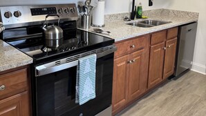 A kitchen with wooden cabinets, stainless steel appliances, a granite countertop, and a built-in dishwasher. - Newly Renovated near everything in Downtown Atlanta and Mercedes Stadium.  (Atlanta)