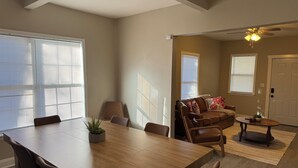 A spacious living room with a wooden dining table, comfortable seating, and a ceiling fan. - Newly Renovated near everything in Downtown Atlanta and Mercedes Stadium.  (Atlanta)